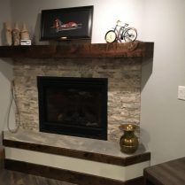 Fireplace with stone tile, dark wood mantel, and a small decorative bicycle.