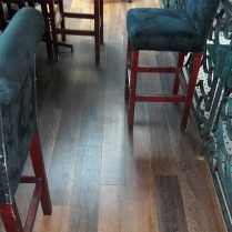 Wooden floor with bar stools and a partial view of a wrought iron railing.