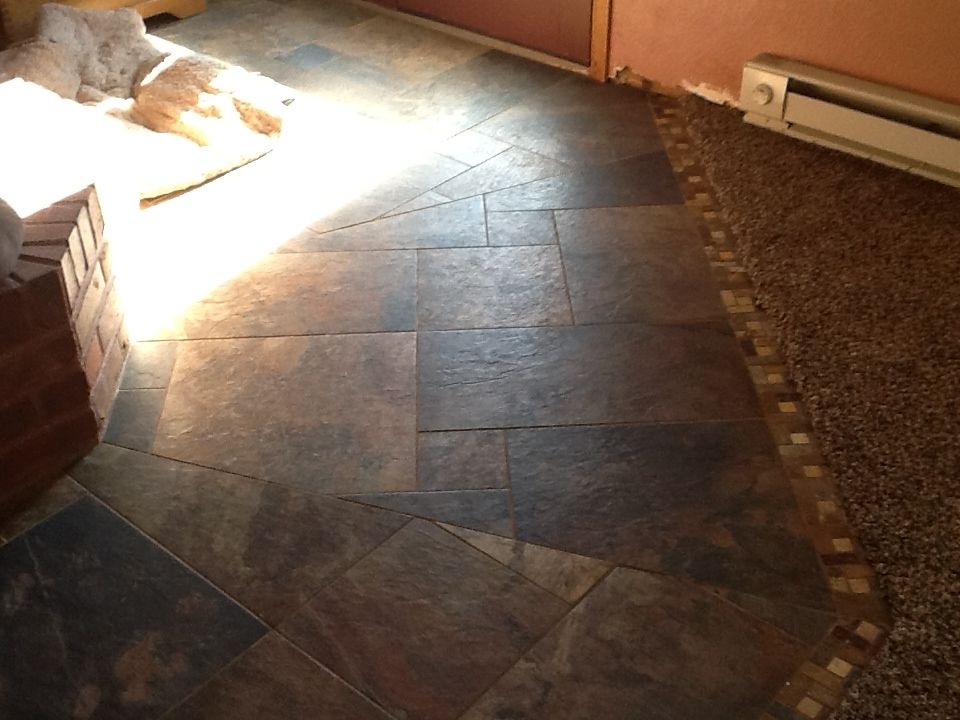 Stone tile flooring transitions to carpet, with a heater and a brick element in view.