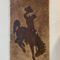 Silhouette of a cowboy riding a bucking bronco on a brown rug.