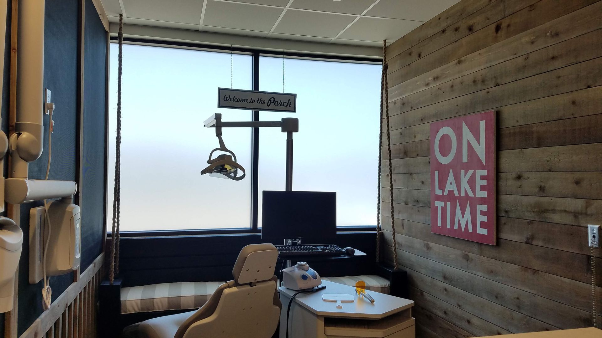 Cozy lakeside café seating with large window, wooden walls, and pink “ON LAKE TIME” sign