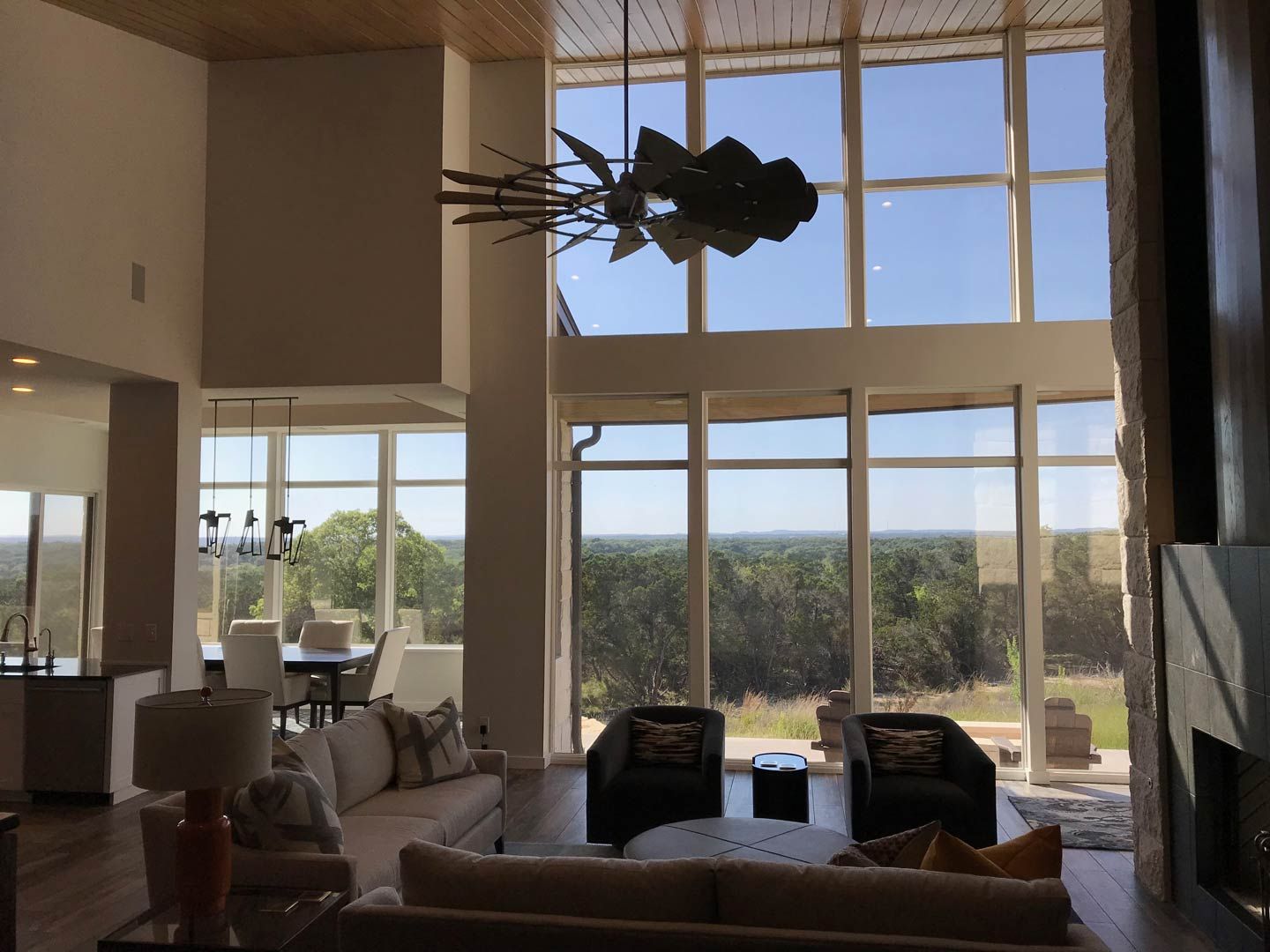 Modern living room with floor-to-ceiling windows overlooking a landscape and a large hanging sculpture overhead