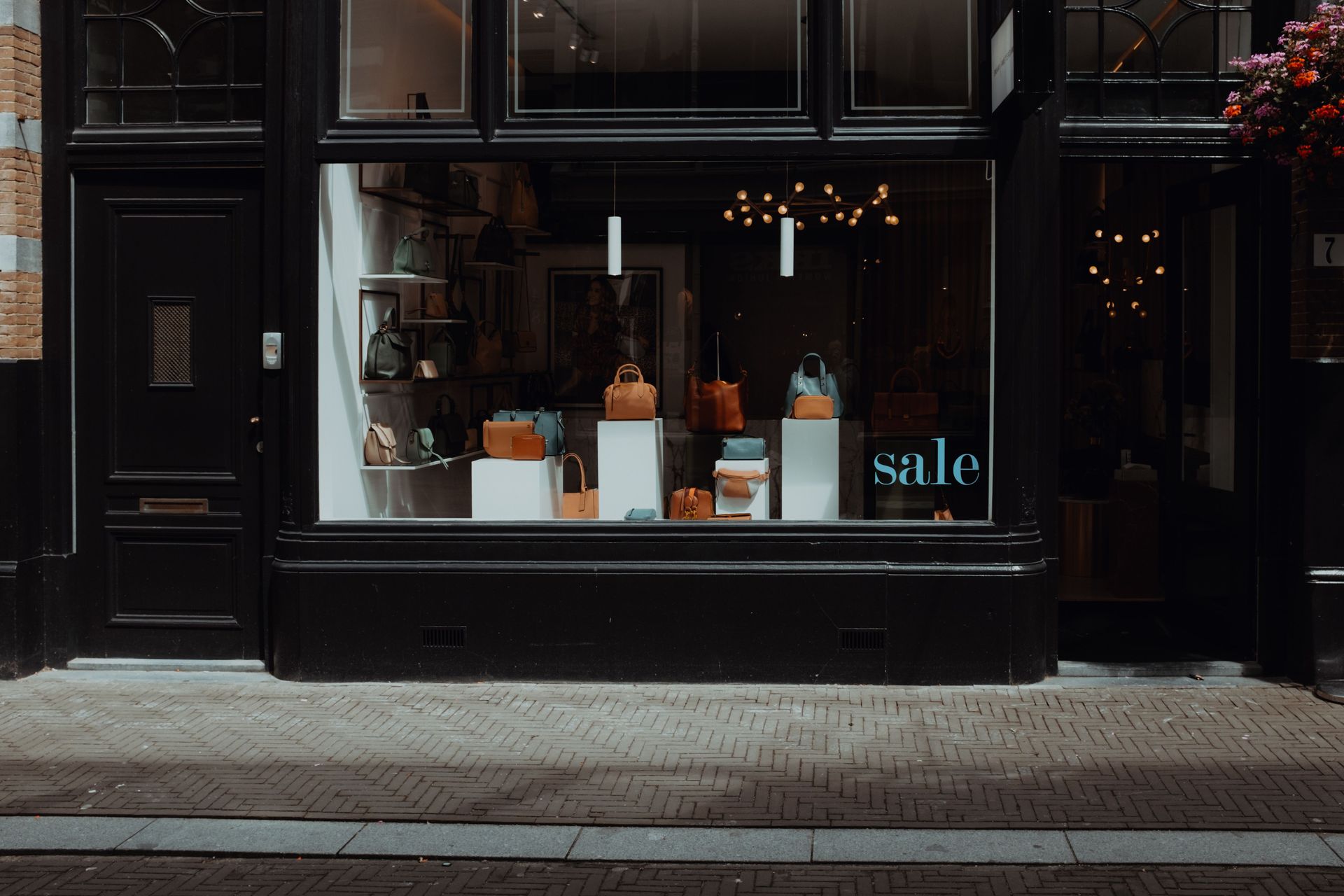 Dark storefront window display with orange items and a small blue “sale” sign