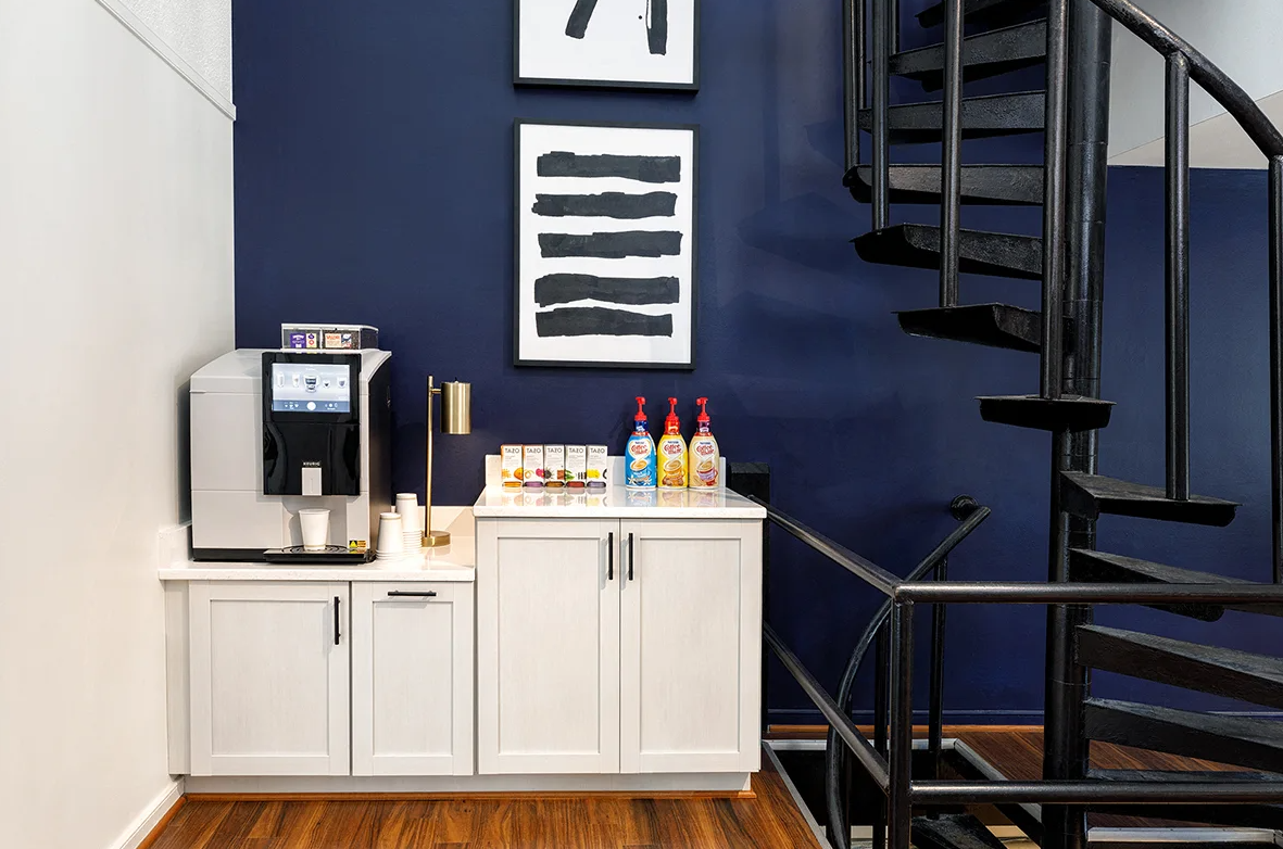A room with a spiral staircase and a coffee maker.