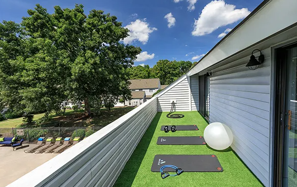 A balcony with exercise mats and a ball on it