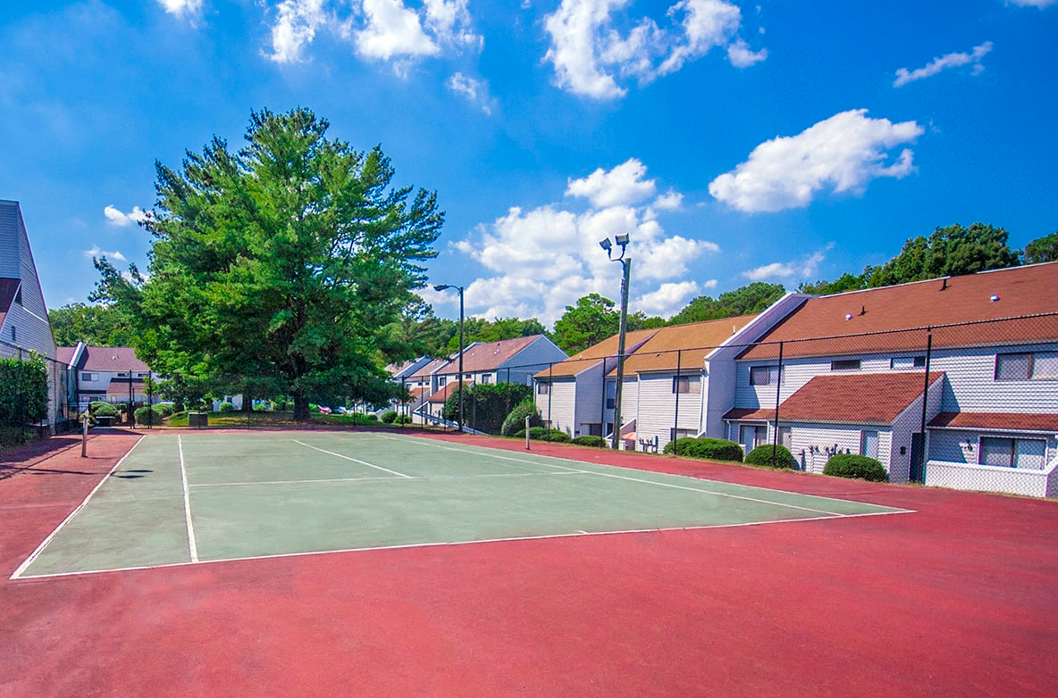 There is a tennis court in the middle of a residential area.