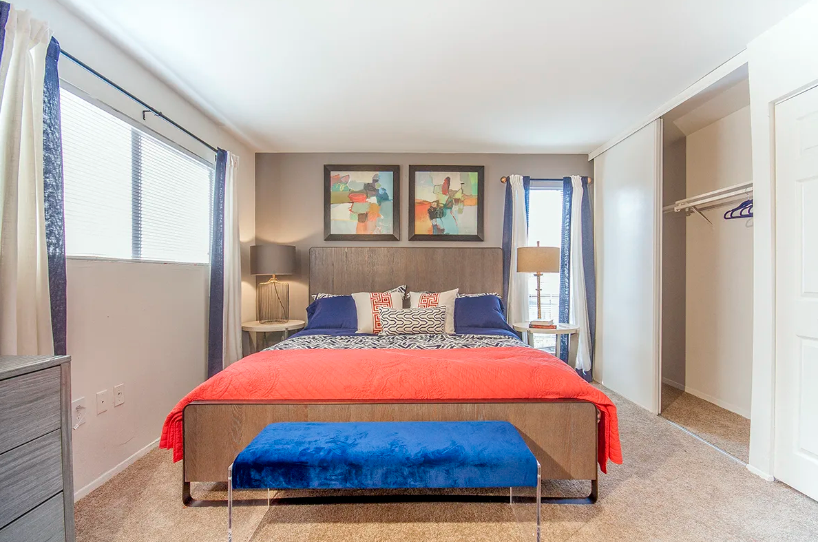 A bedroom with a large bed and a blue bench.