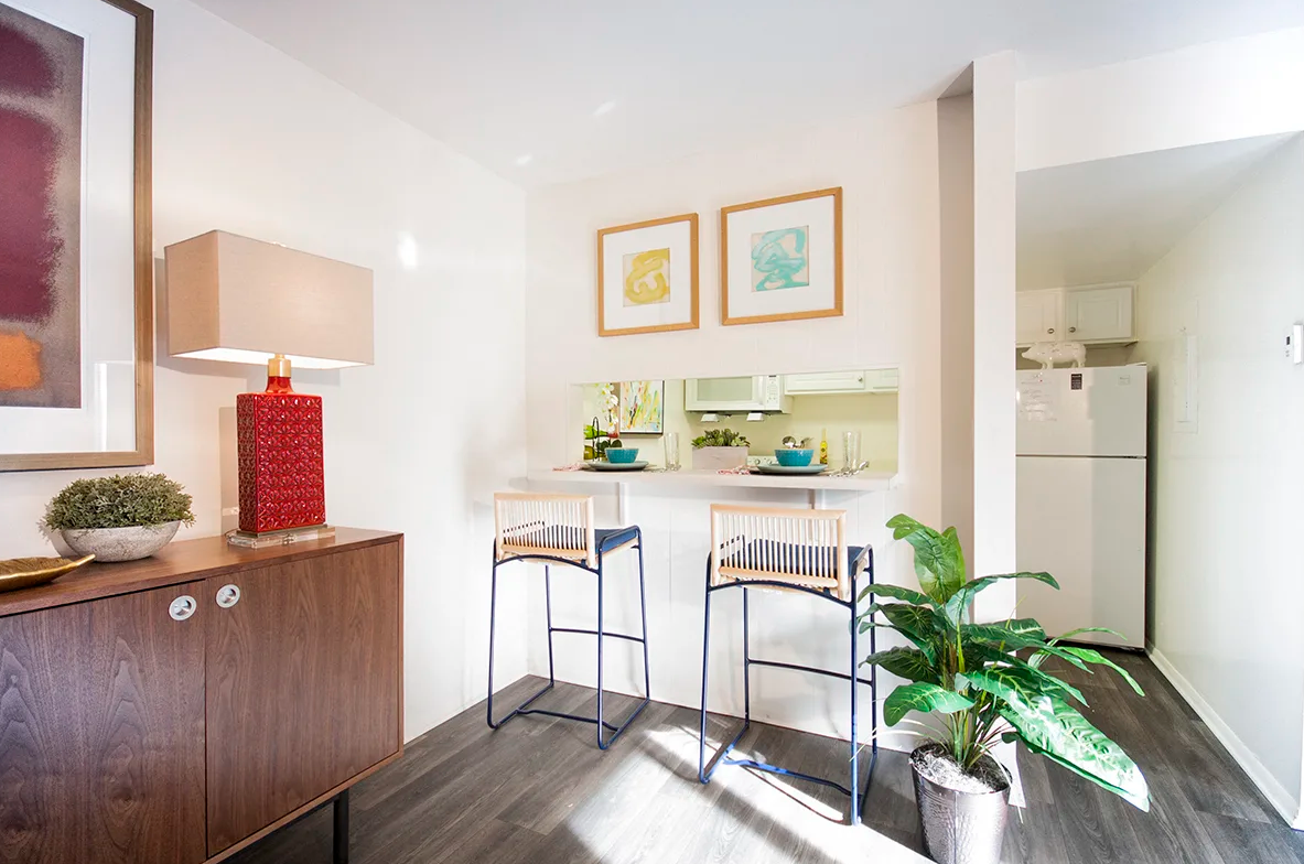 A living room with two bar stools and a dresser.