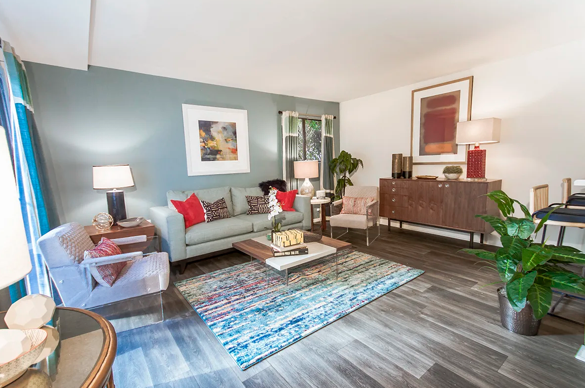 A living room with a couch , chairs , coffee table and rug.