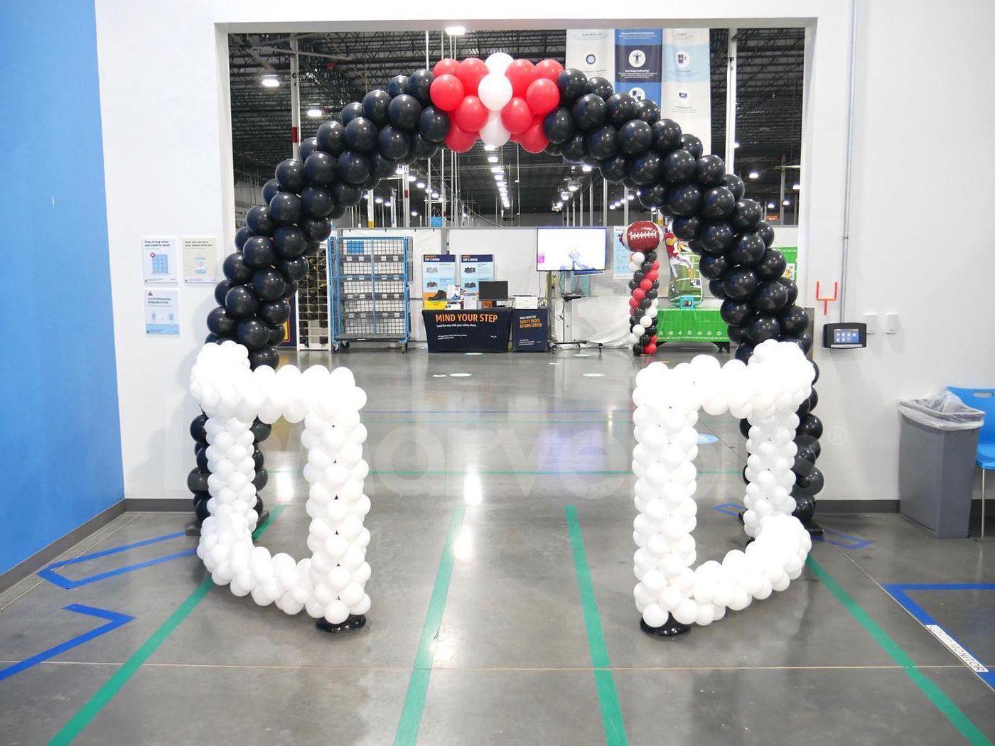 A large arch made of black and white balloons in a warehouse