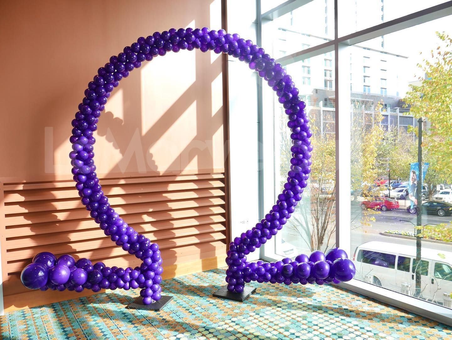 A purple balloon sculpture is sitting in front of a window.