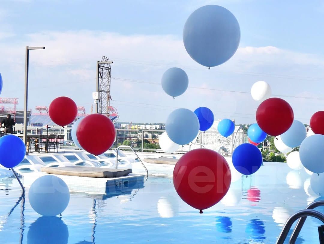 A bunch of balloons are floating in a pool