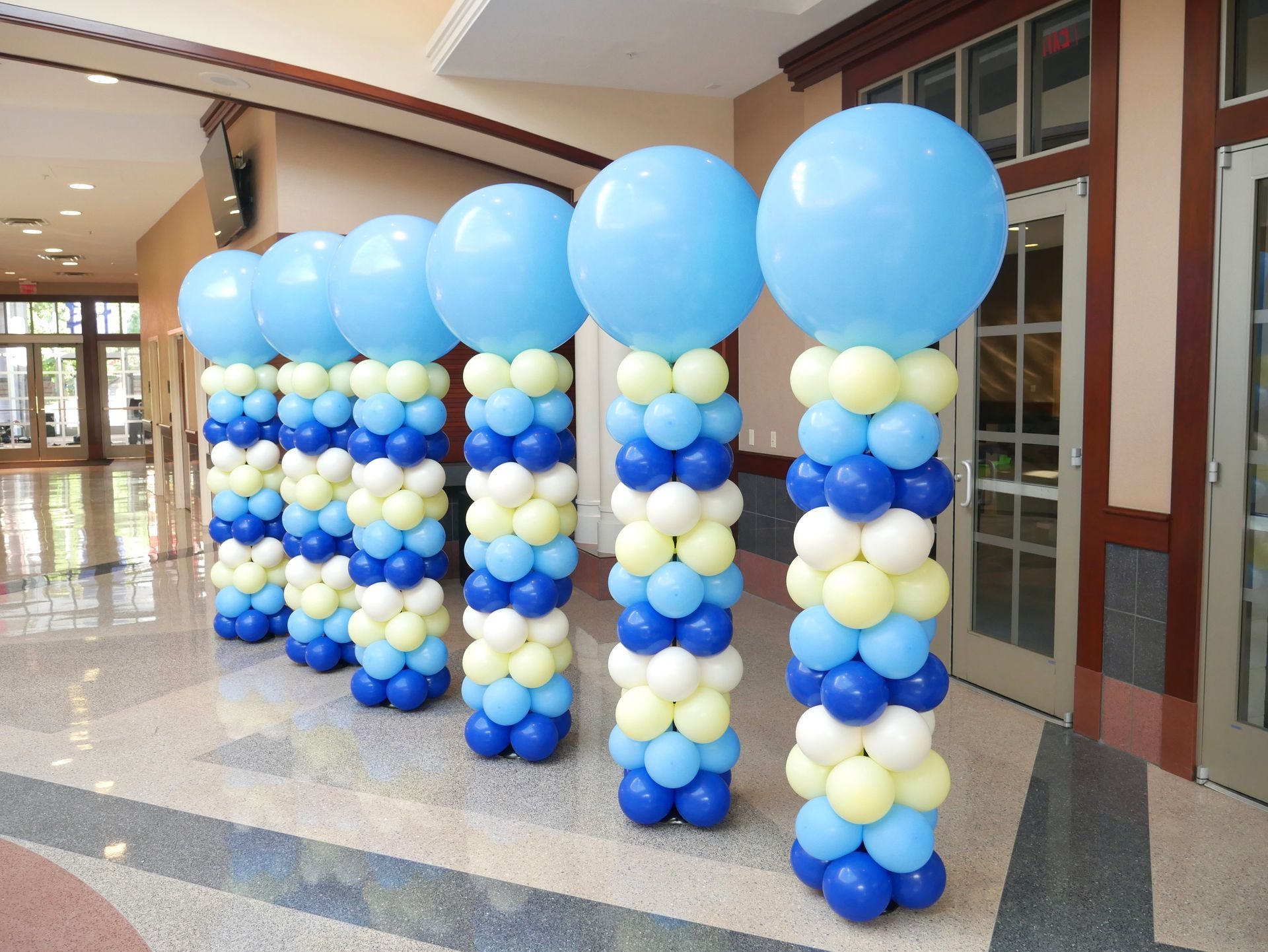 A row of blue and white balloon columns in a hallway