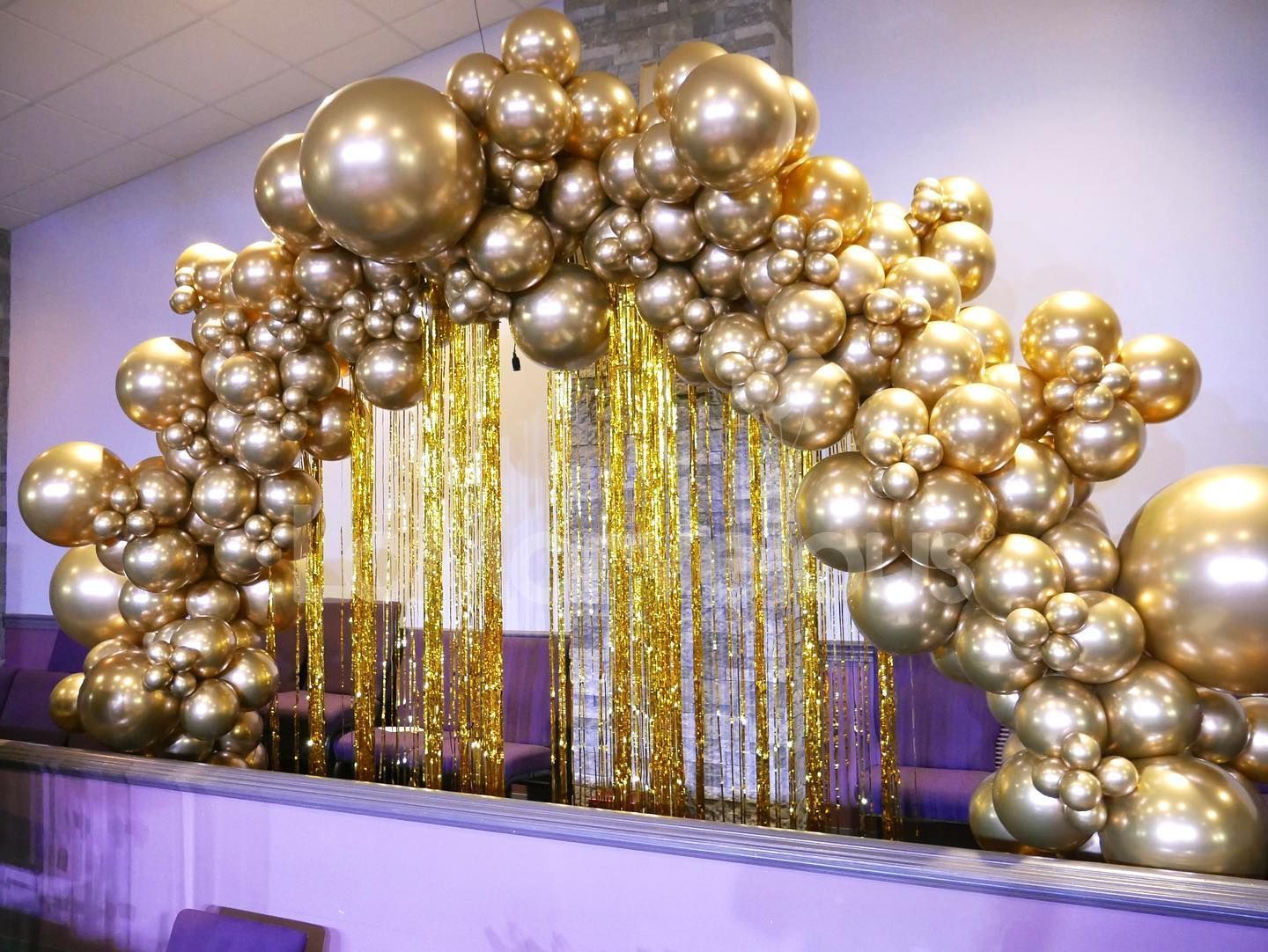 A room decorated with gold balloons and gold tinsel.