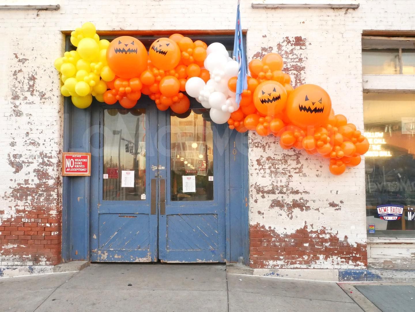 A blue door is decorated with balloons and pumpkins for halloween