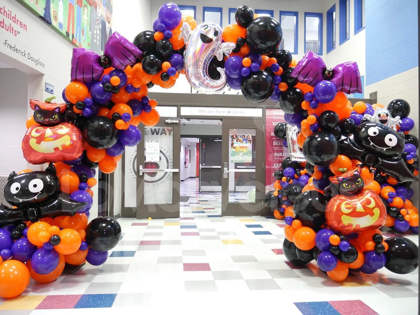 A bunch of halloween balloons are sitting in a hallway.