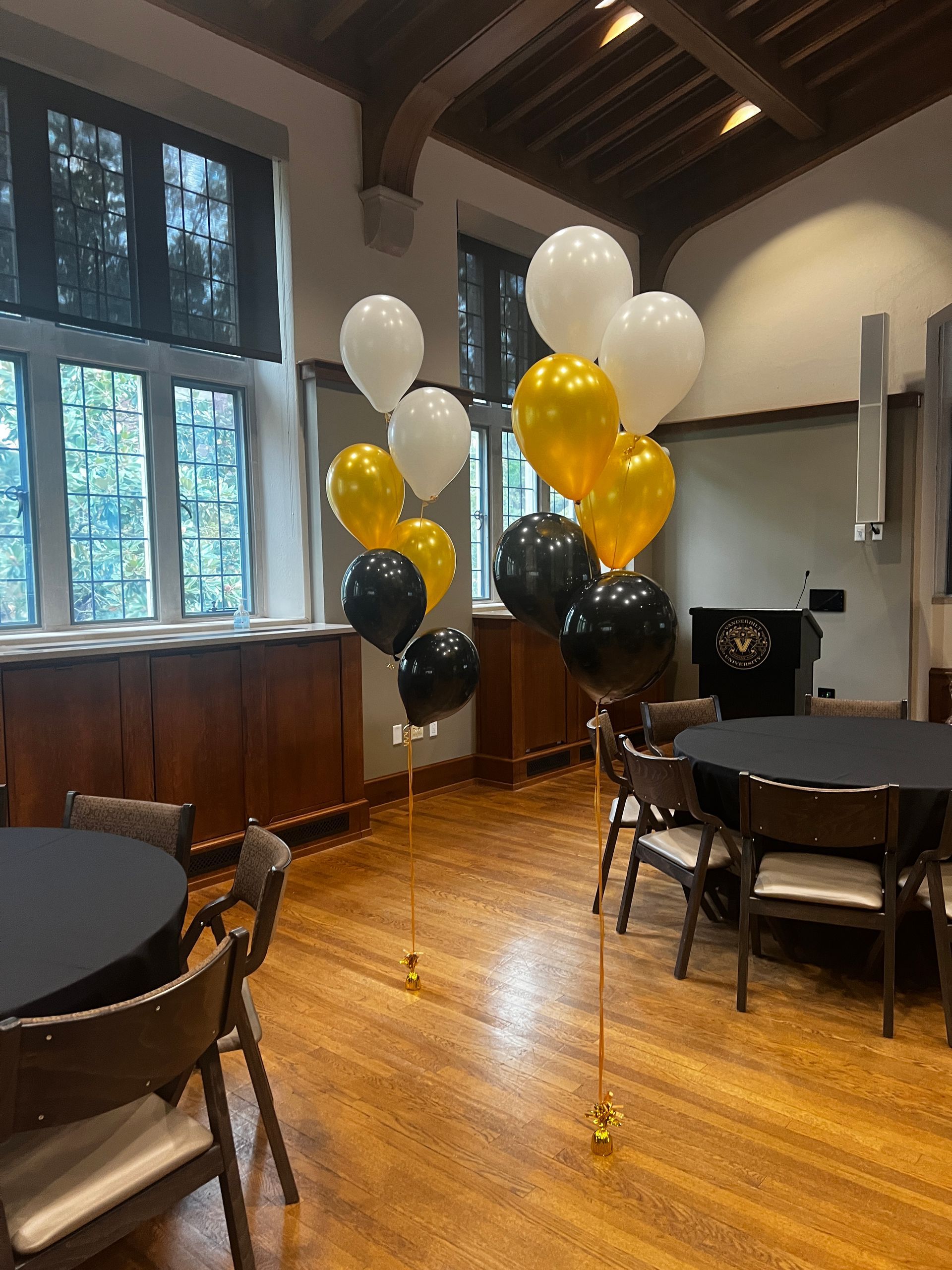 A room with tables and chairs and balloons on the floor.