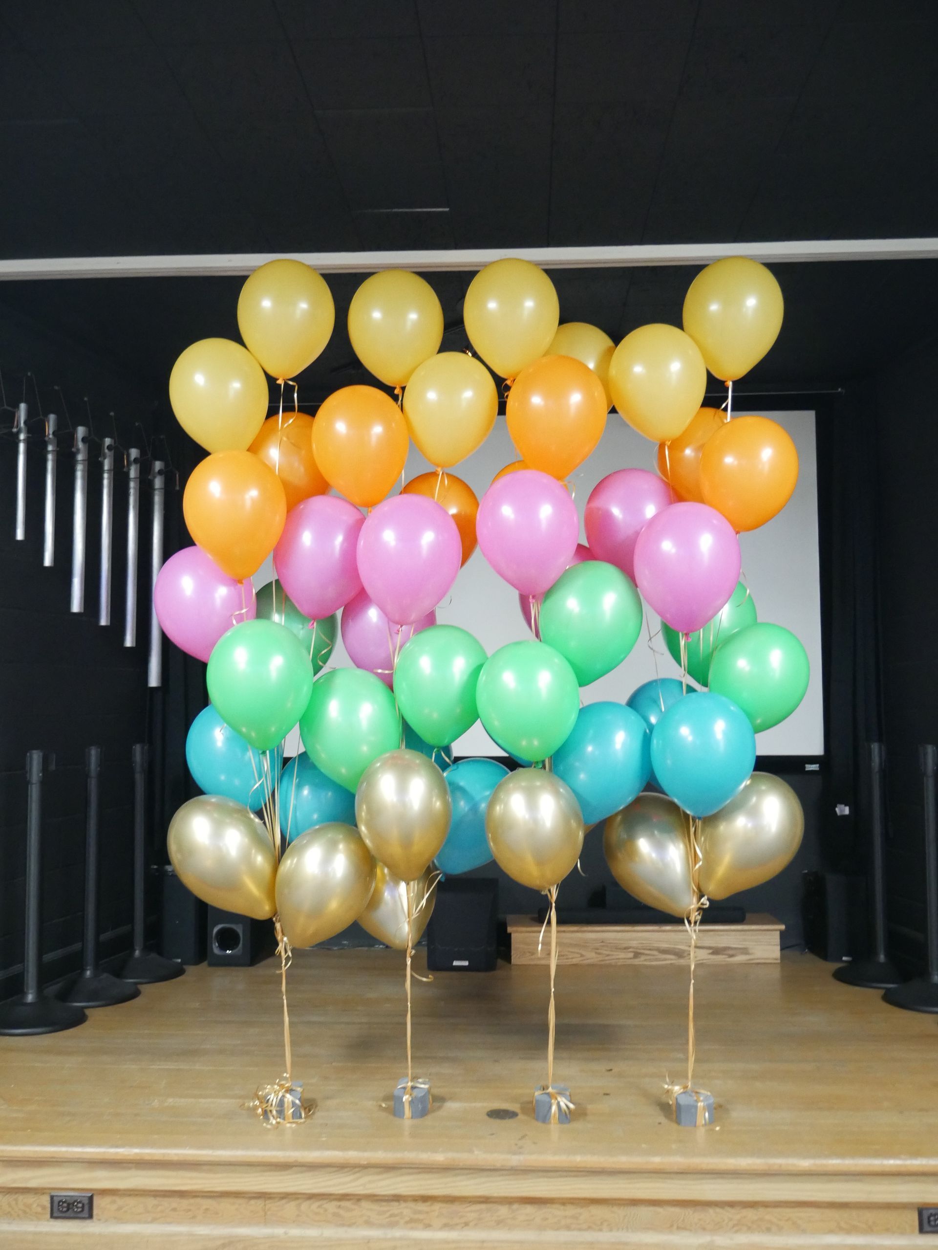 A bunch of colorful balloons on stands on a stage