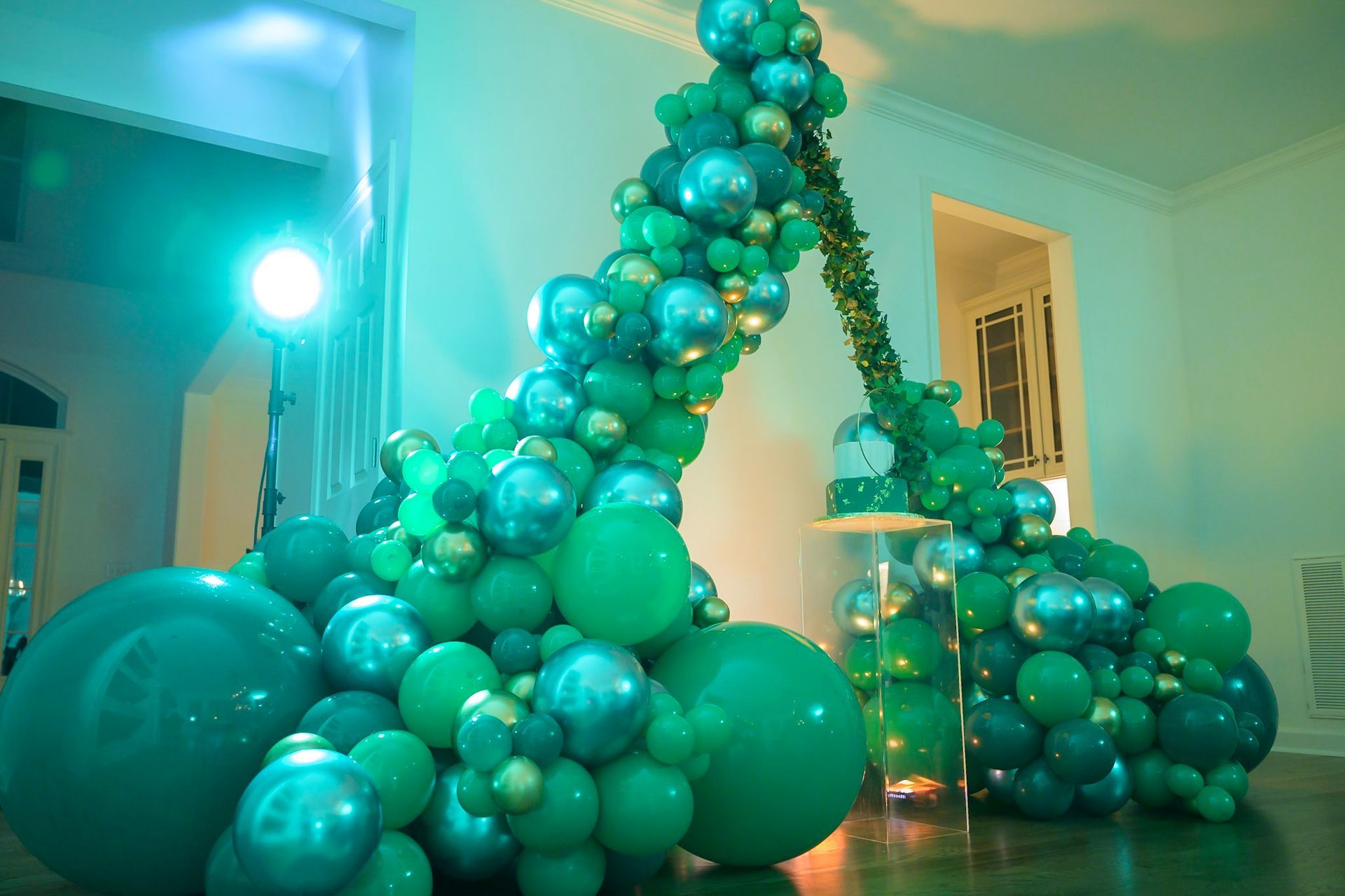 A bunch of green balloons are sitting on the floor in a room.