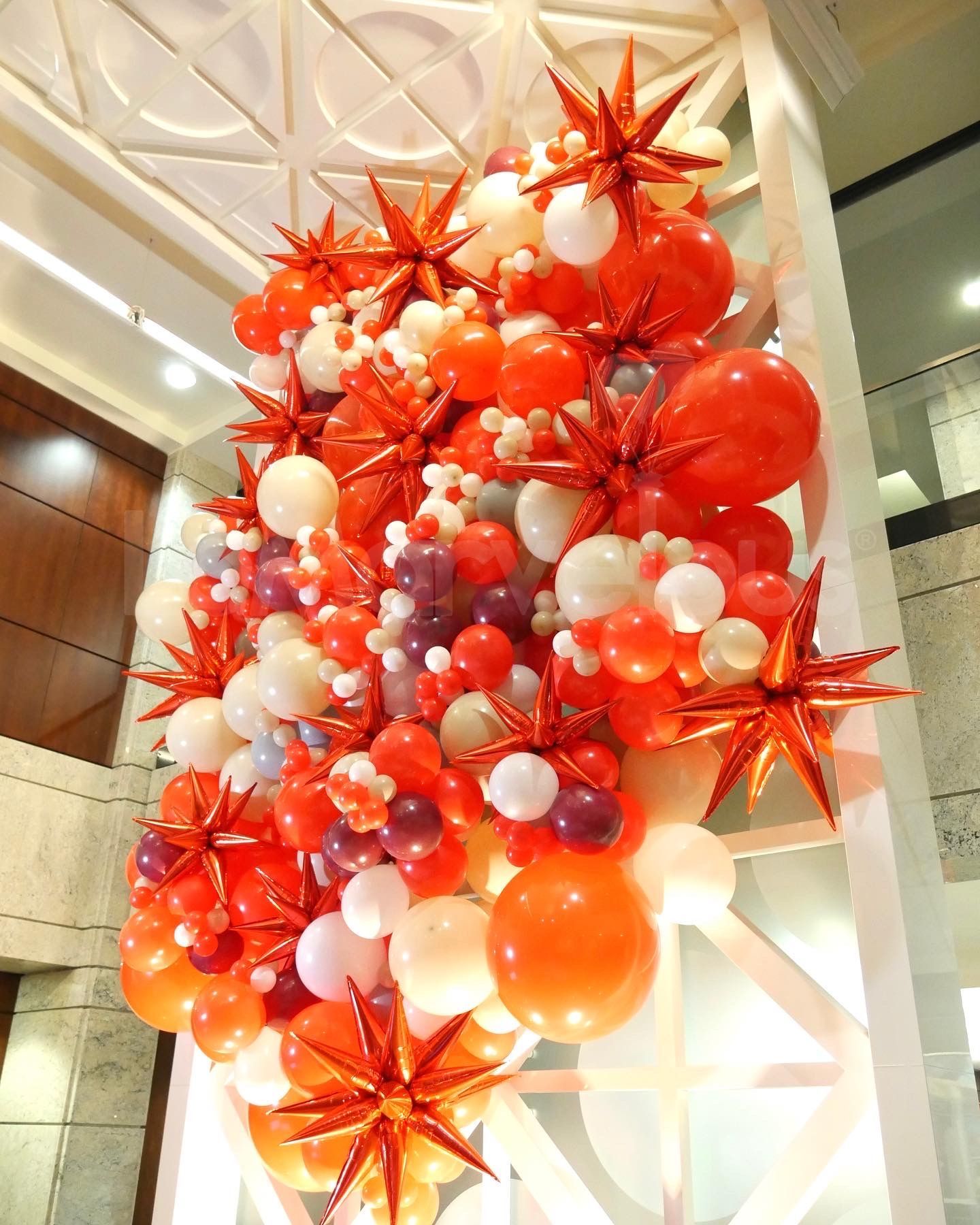 A bunch of red and white balloons hanging from the ceiling
