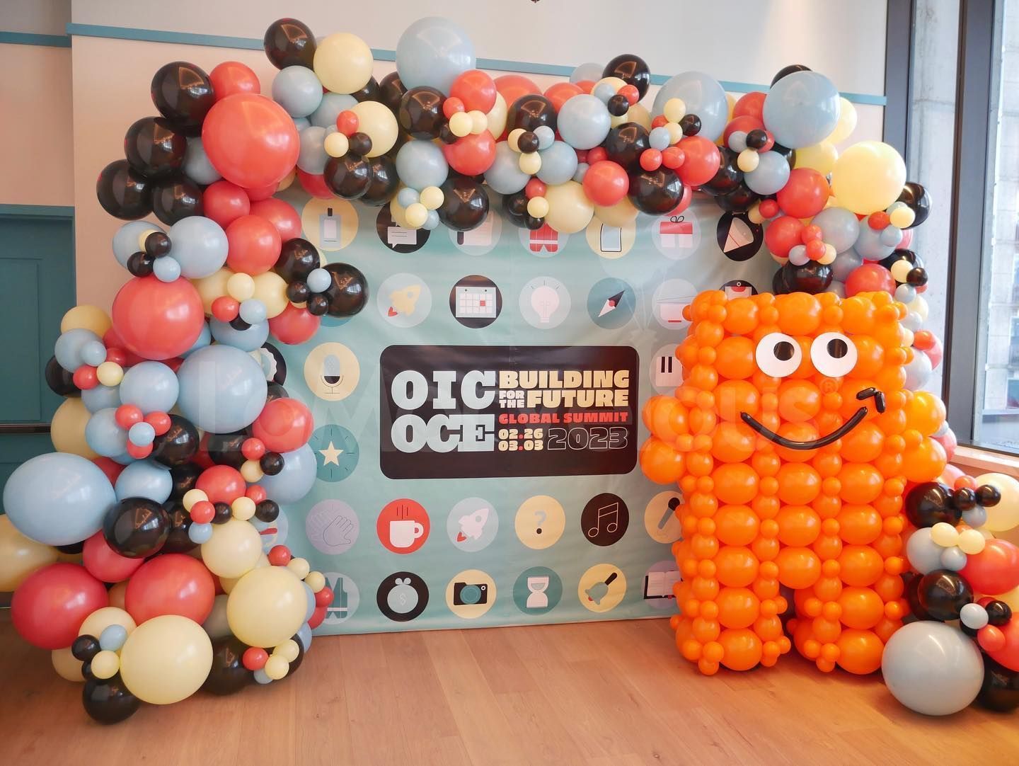 A balloon monster is standing in front of a wall covered in balloons.