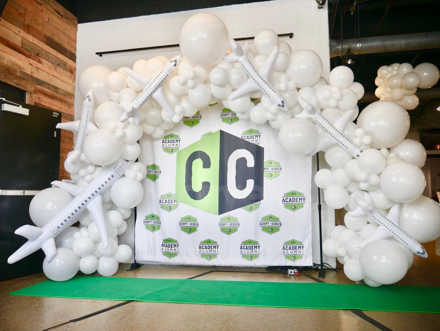 A bunch of white balloons are sitting in front of a sign that says cc