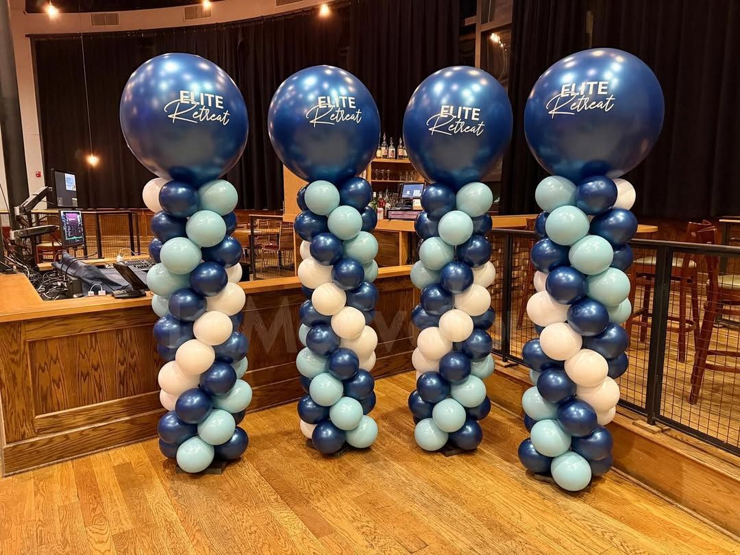 Four balloon columns with blue and white balloons, topped with blue balloons displaying a logo.