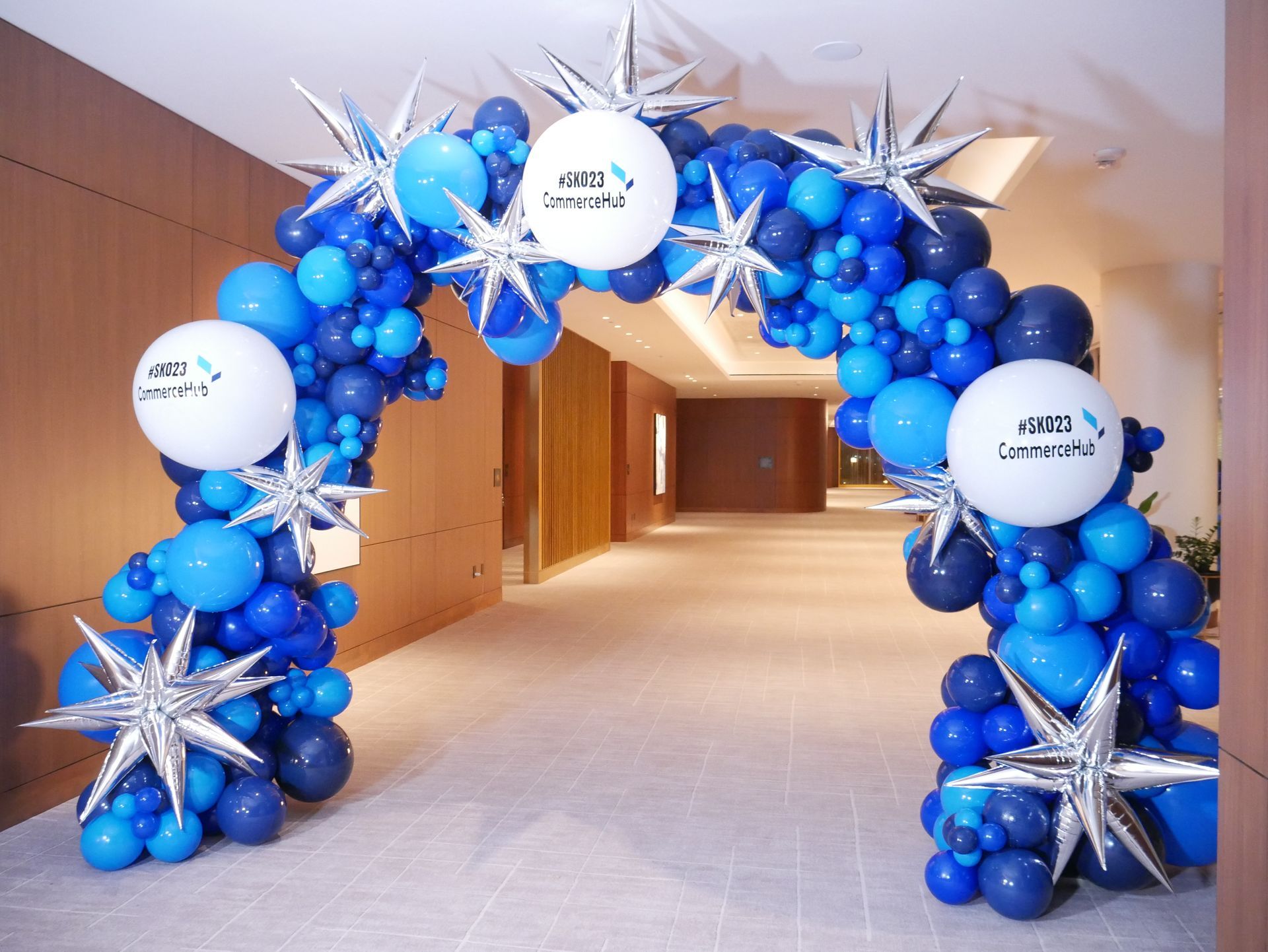 A blue and white balloon arch in a hallway