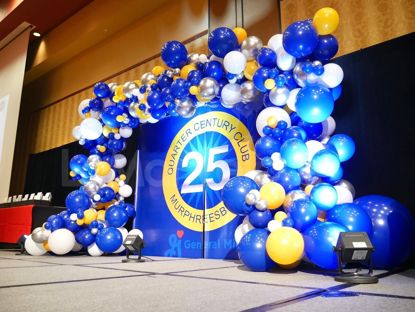A blue and yellow balloon arch with the number 25 on it