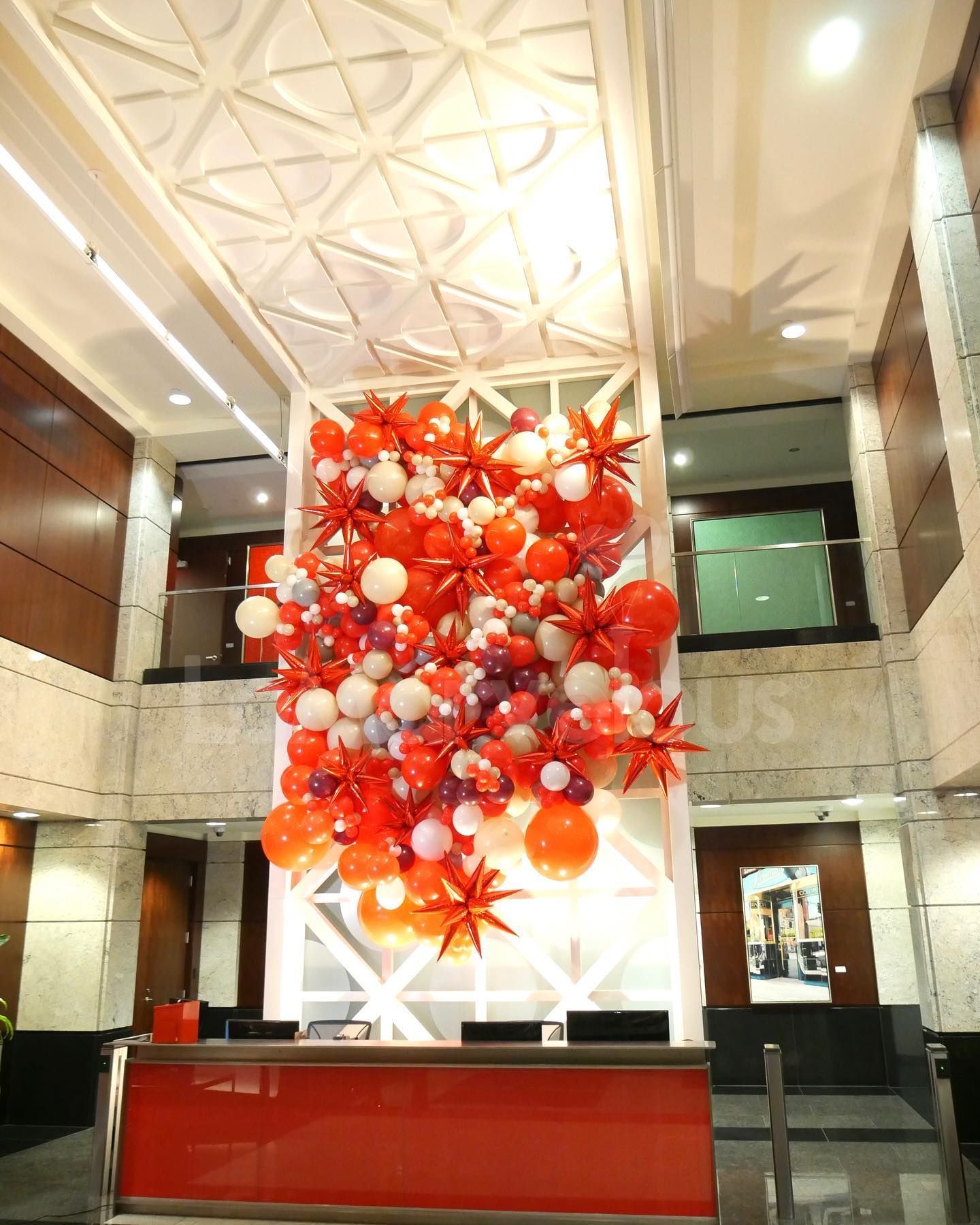 A large display of red and white balloons in a lobby