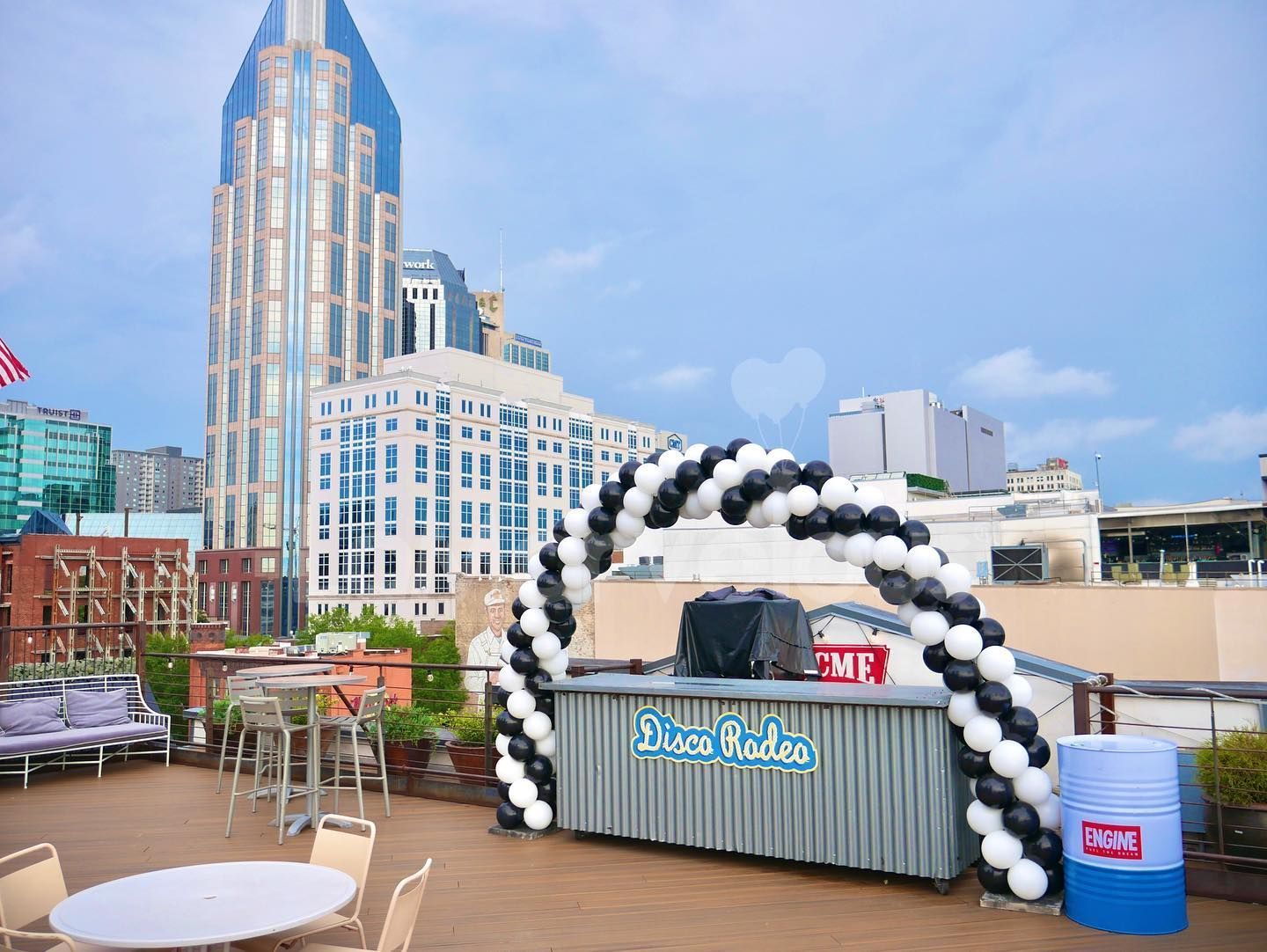 A rooftop bar decorated with black and white balloons and a large building in the background.