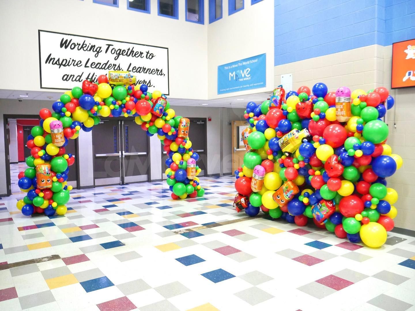 A hallway filled with colorful balloons and a sign that says `` working together to inspire leaders and learners ''.