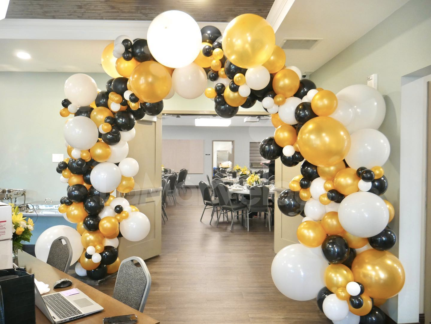 A room decorated with black , gold , and white balloons.