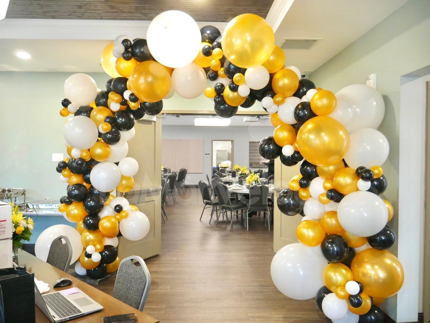 A room filled with balloons and a laptop on a desk.