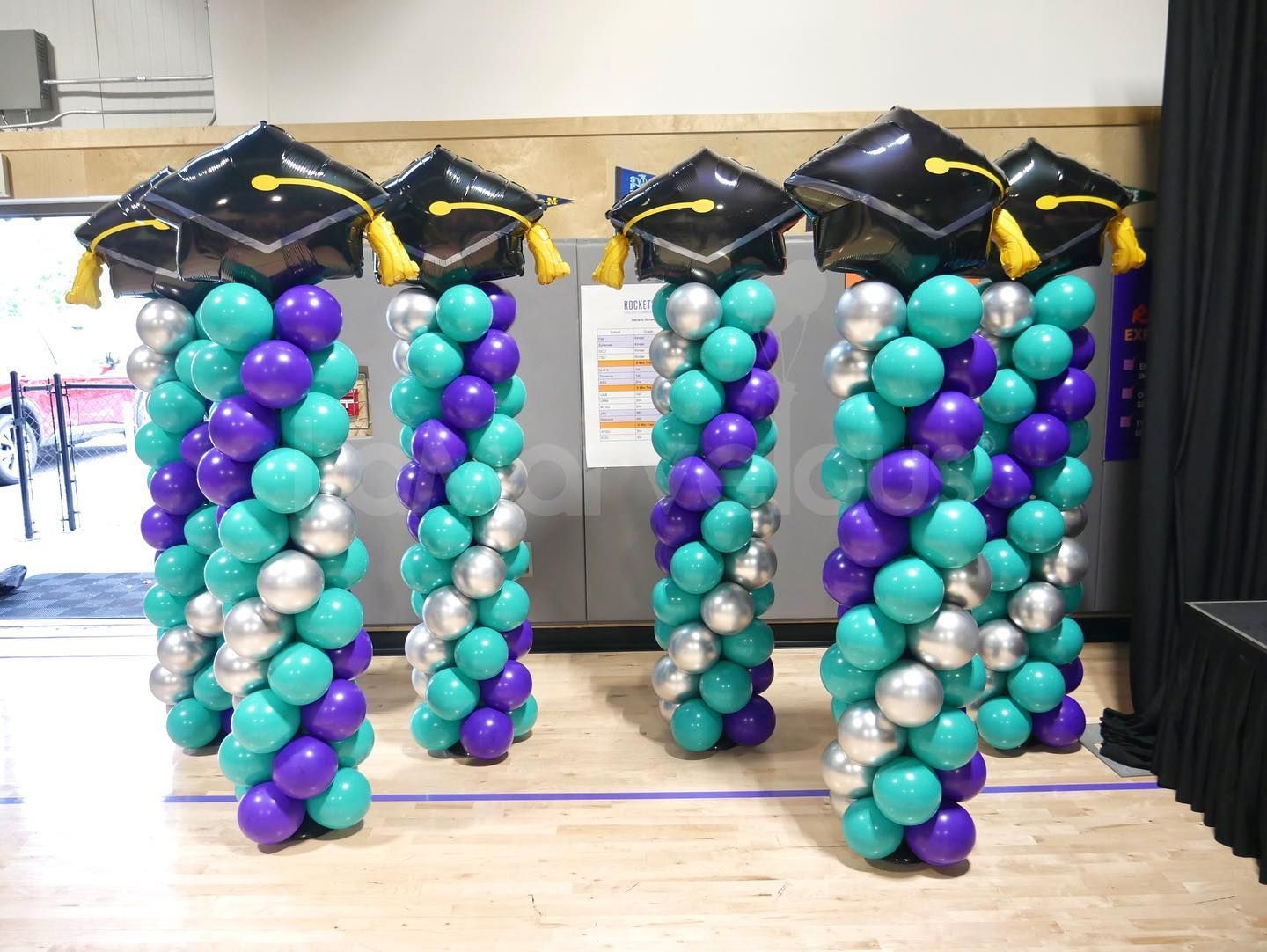 A row of balloons with graduation caps on top of them.