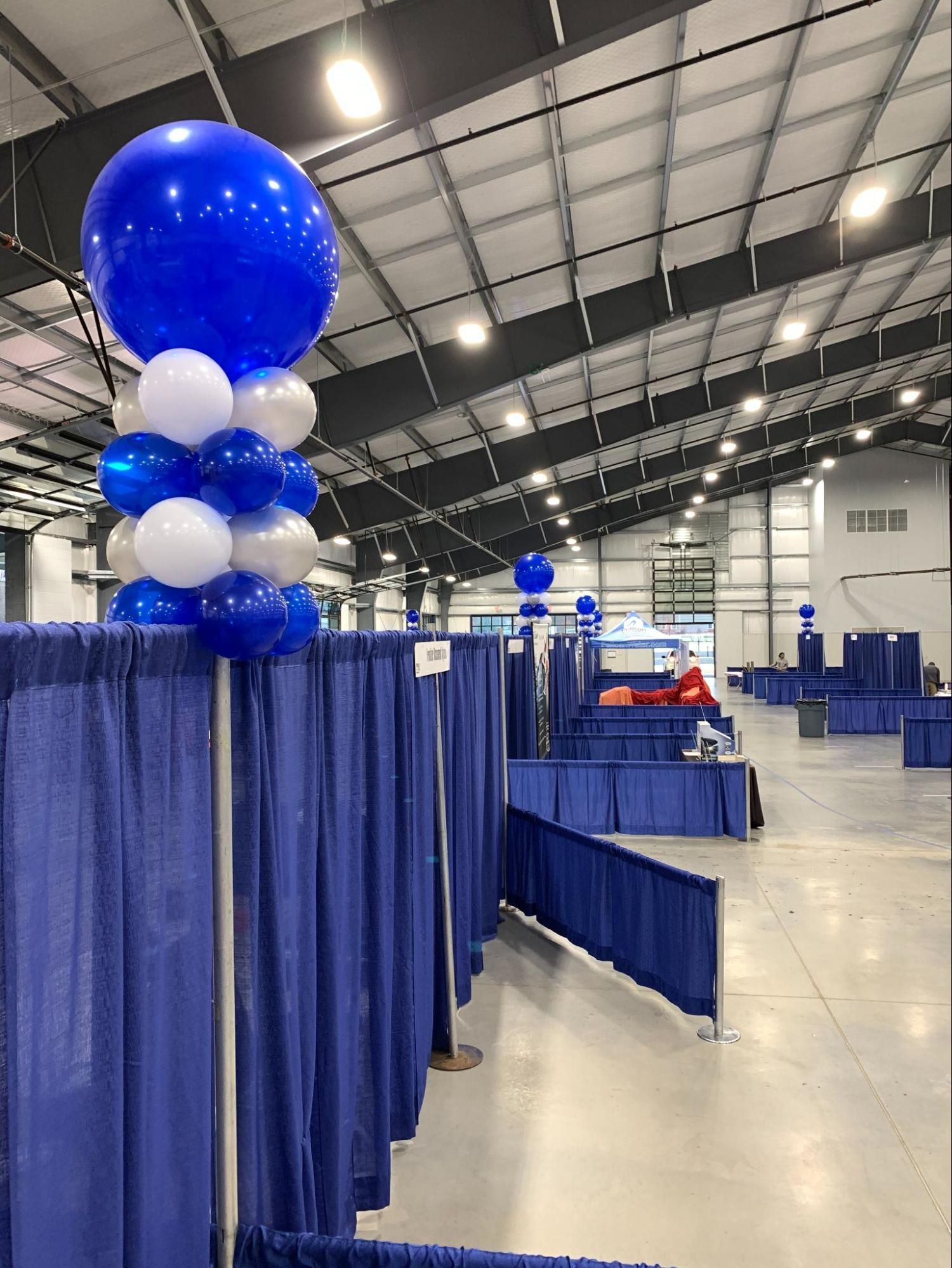 A large room with blue curtains and blue and white balloons.