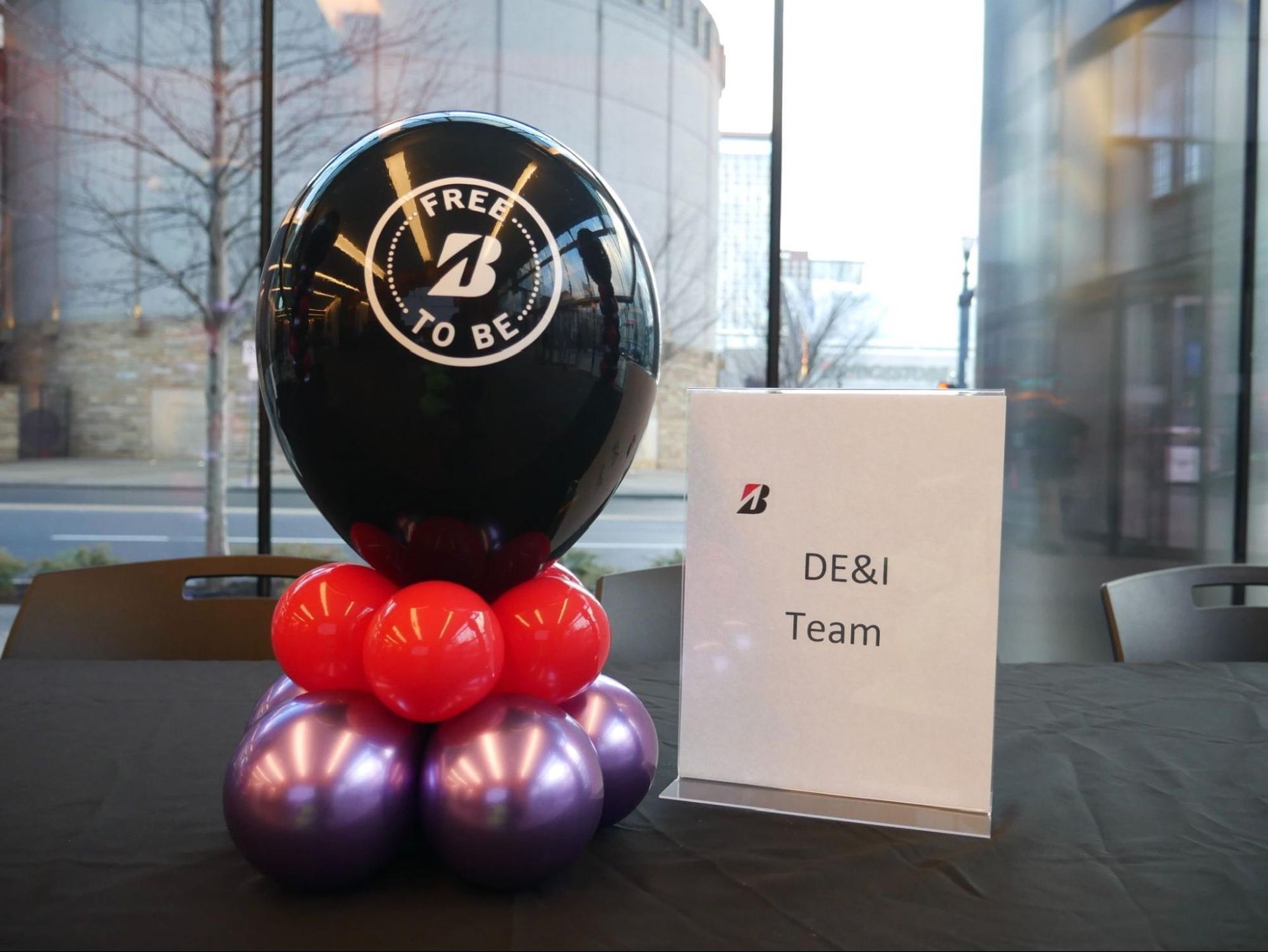 A table with balloons and a sign that says de & i team