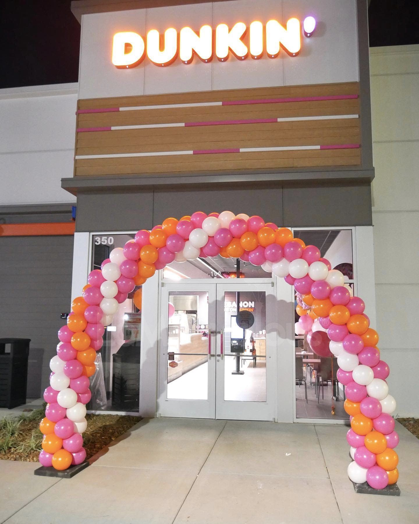 A dunkin ' donuts store with balloons in front of it