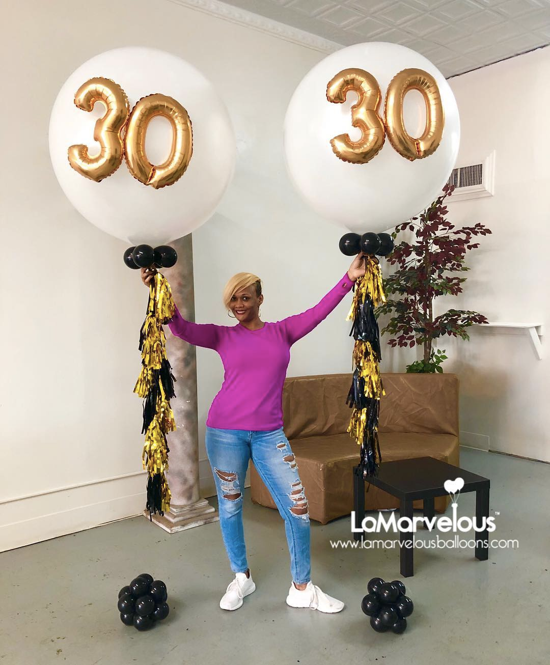 A woman is standing in front of two balloons with the number 30 on them