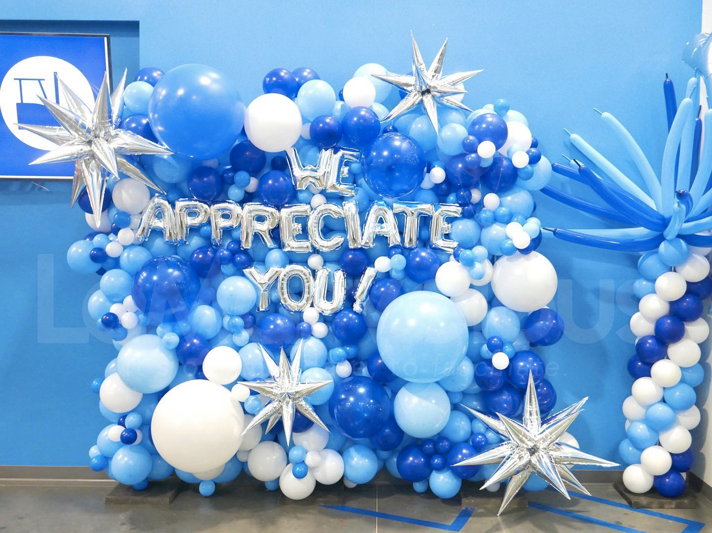 A wall of blue and white balloons with the words `` we appreciate you '' written on them.