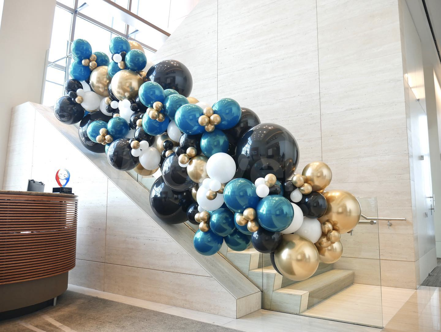 A staircase decorated with blue , black , and gold balloons.