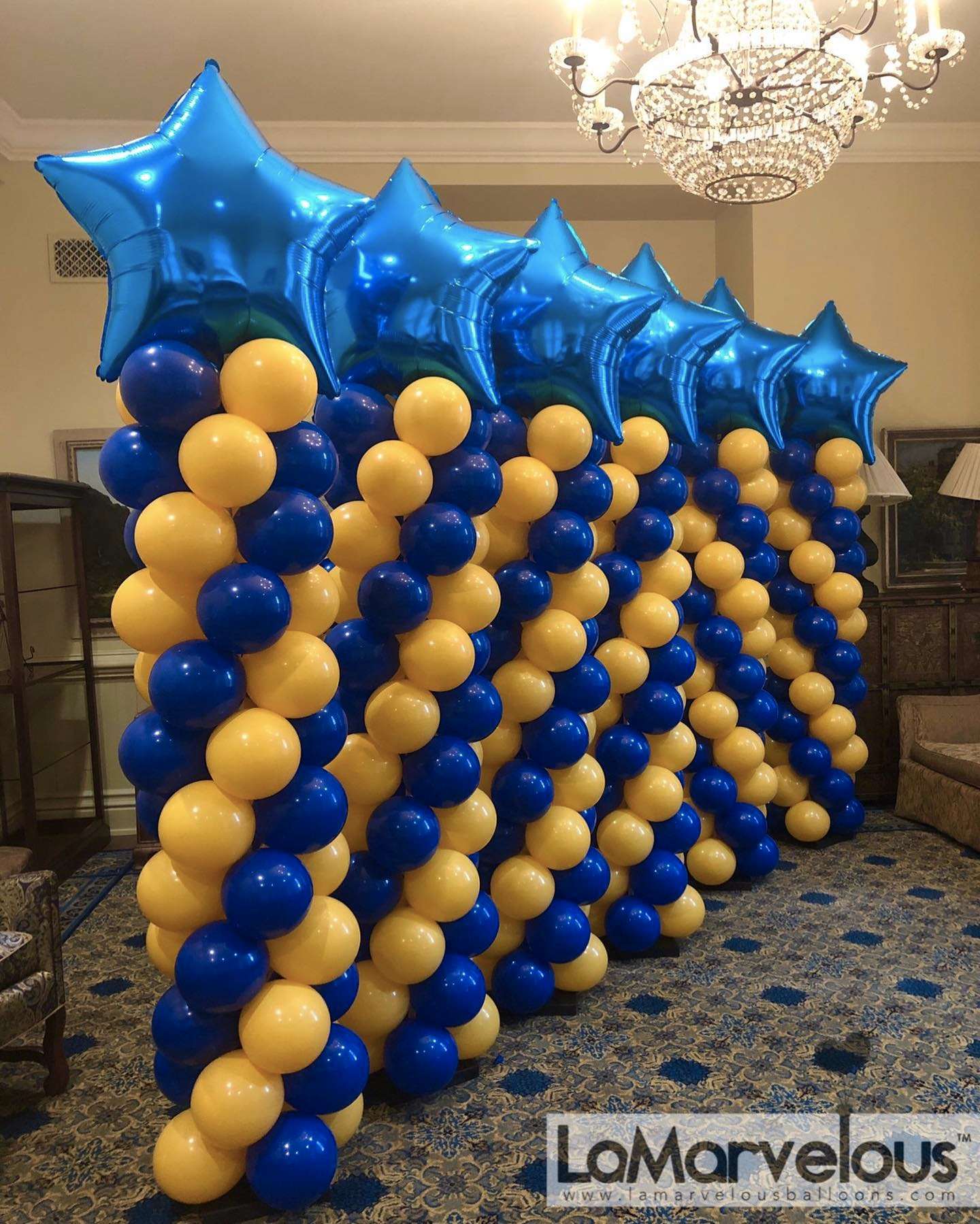 A row of blue and yellow balloons with stars on top