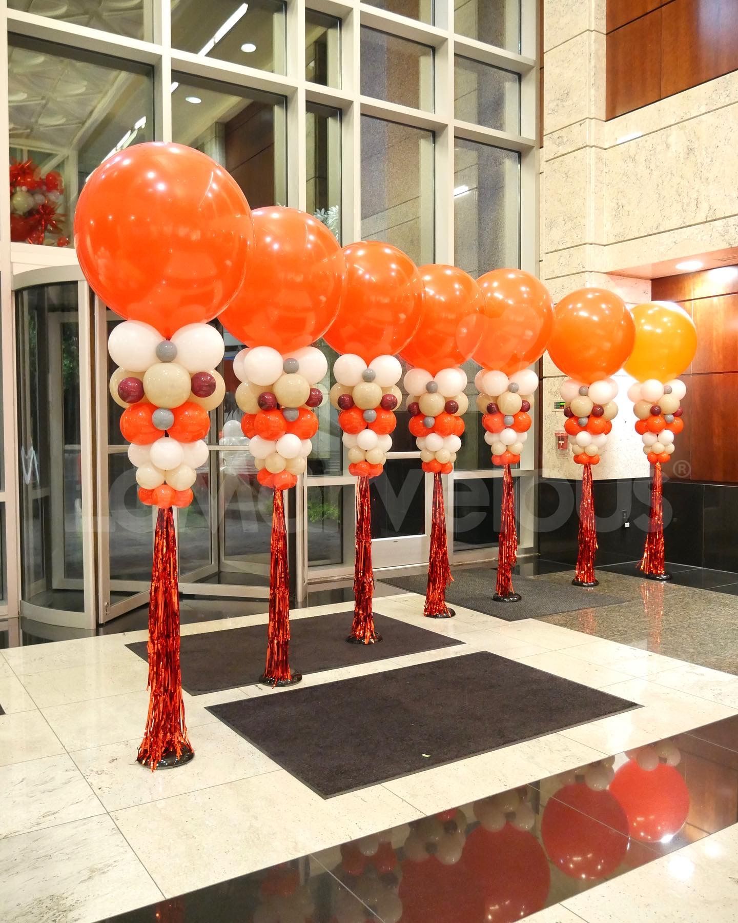 A row of orange and white balloons on red poles