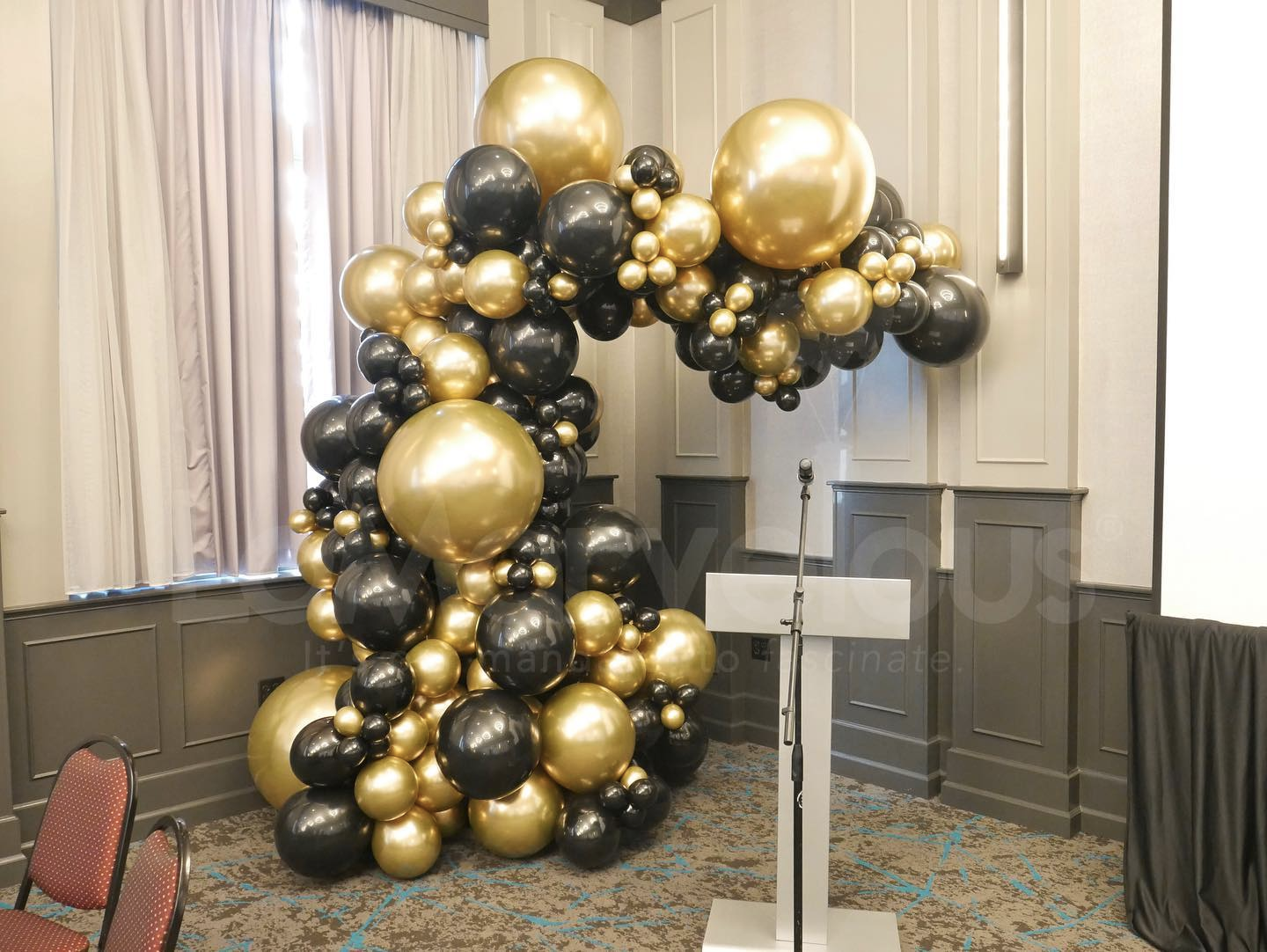 A room decorated with black and gold balloons and a podium.