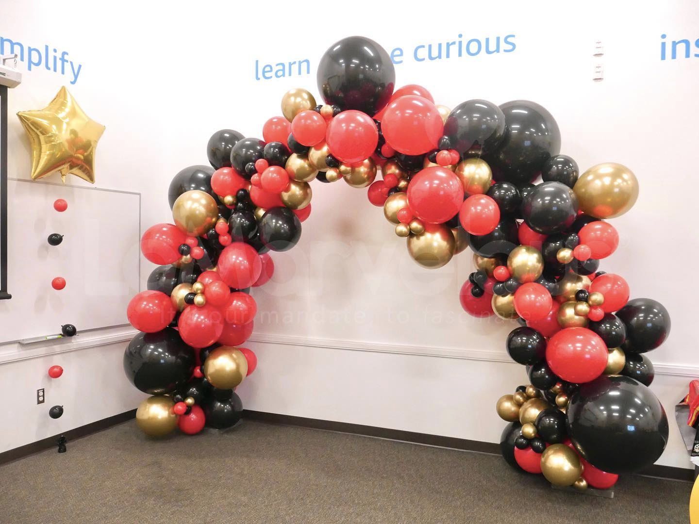 A room decorated with red , black and gold balloons