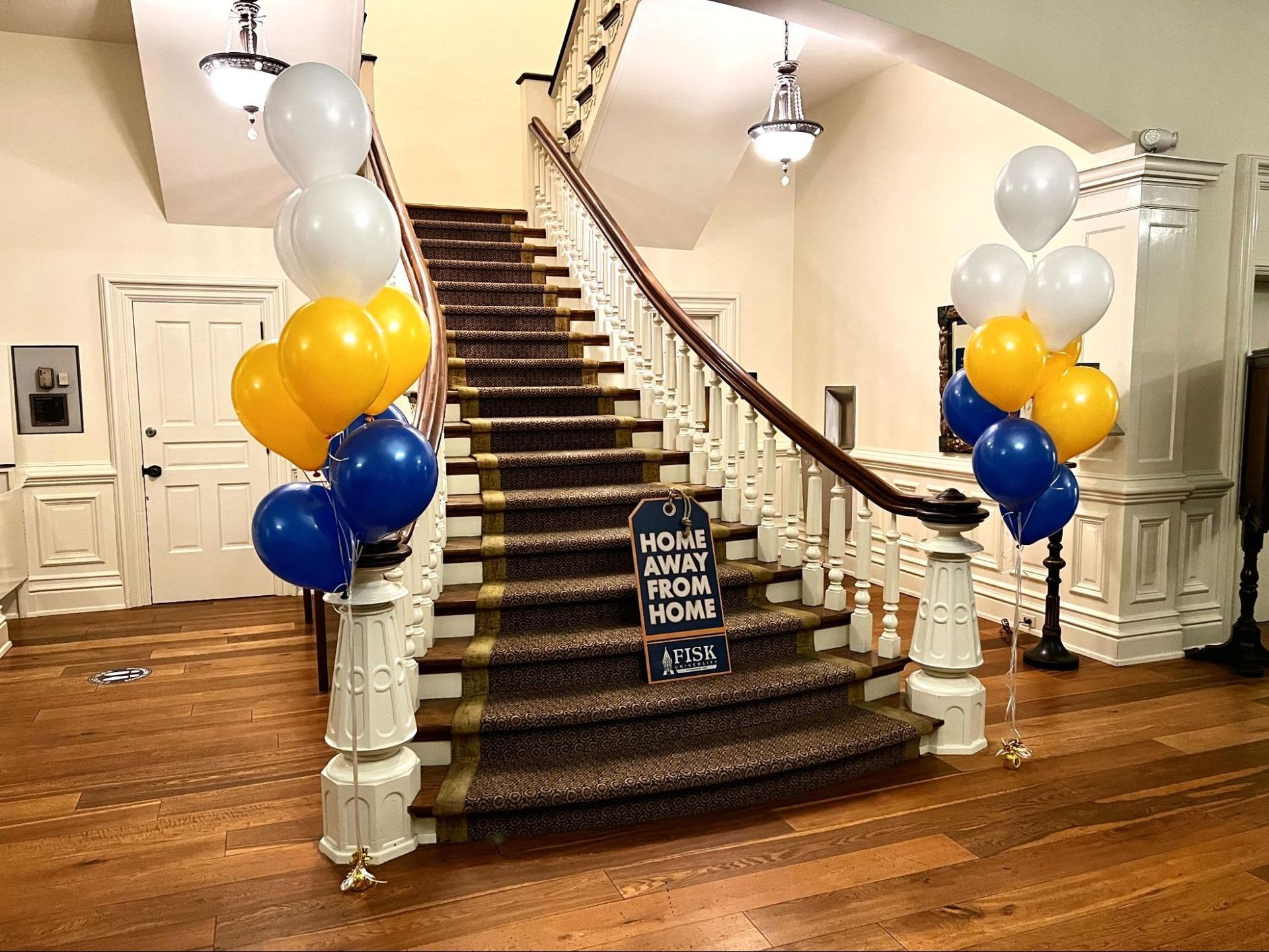 A staircase decorated with balloons and a sign that says