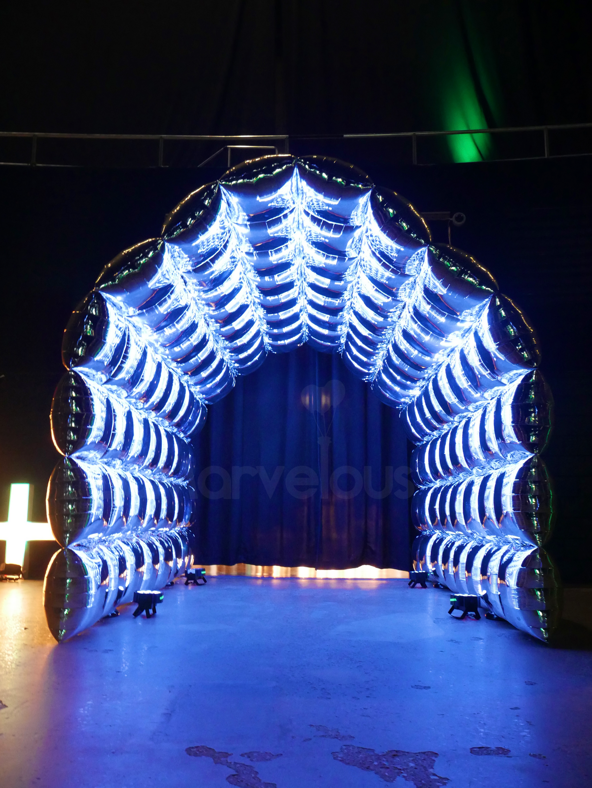 A tunnel made of balloons is lit up at night