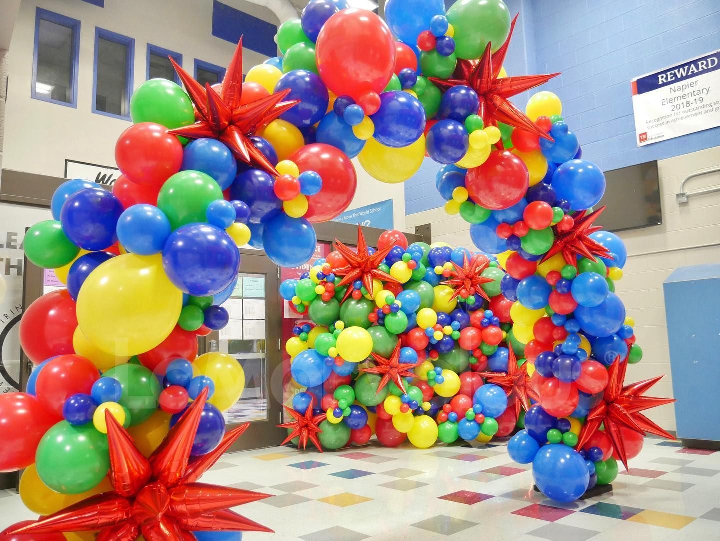 A large arch made of colorful balloons in a room.