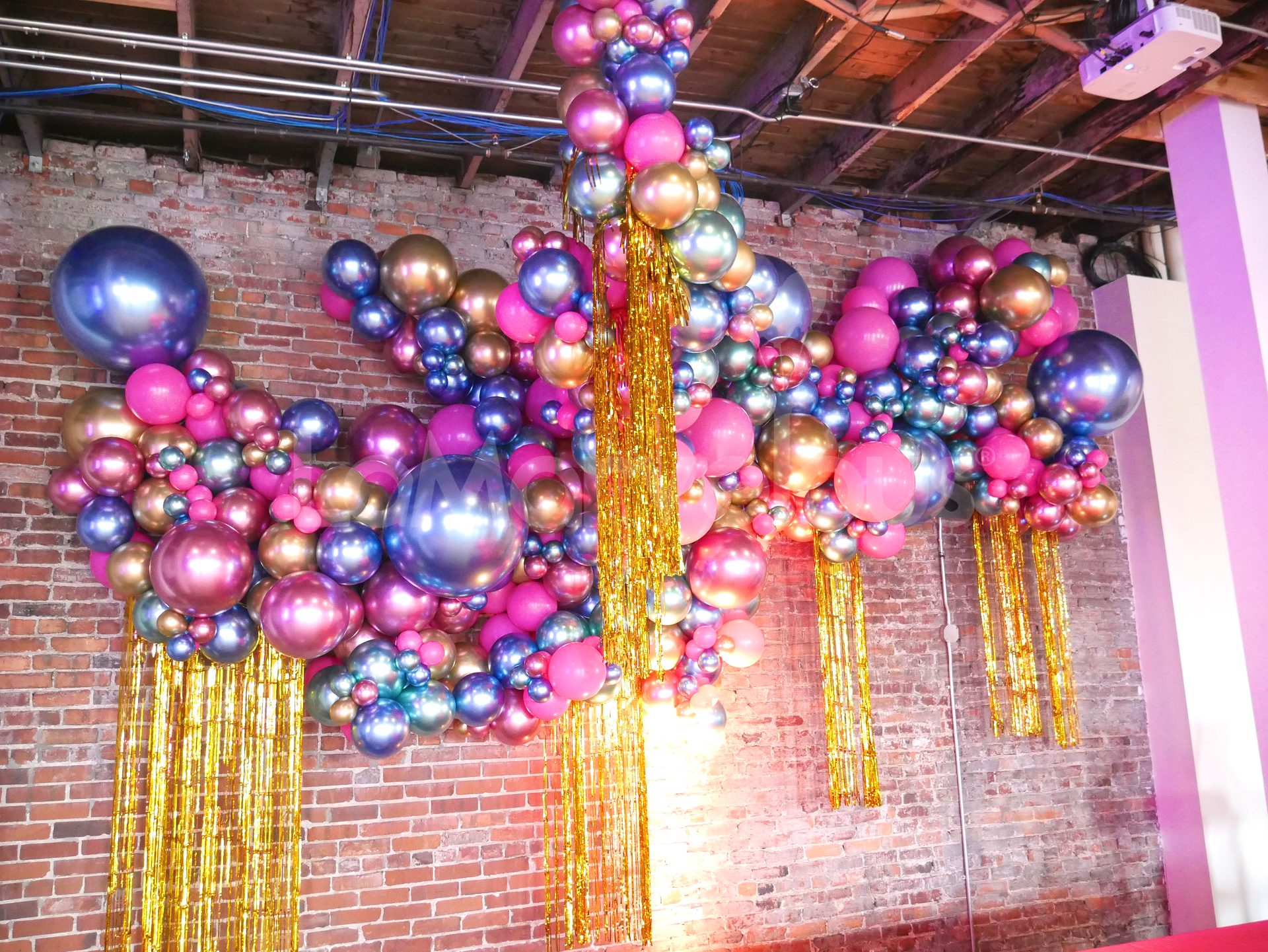 A bunch of balloons are hanging from the ceiling of a room.