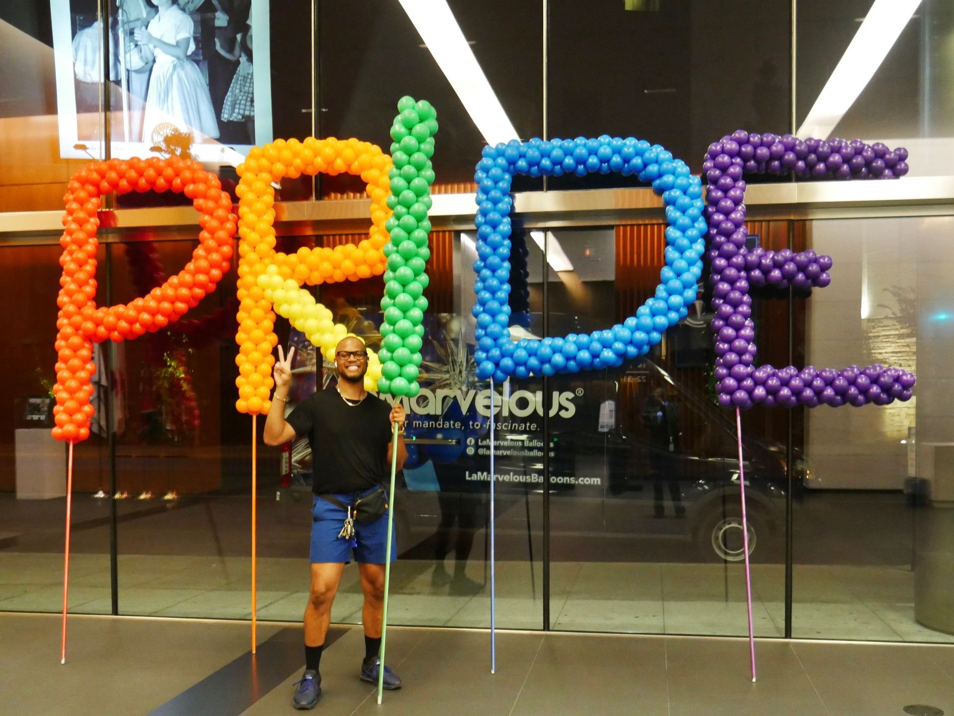 A man stands in front of a sign that says pride